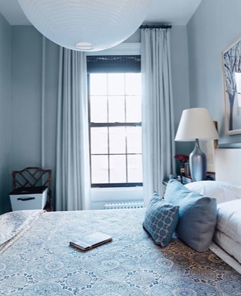 dormitor cu pereti de culoare bleu, cu perdele si lustra albe si elemente de decor albe si albastre 