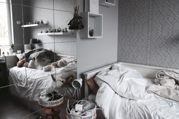 dormitor cu pereti gri , pat alb, mobila si obiecte de decor albe si o oglinda mare