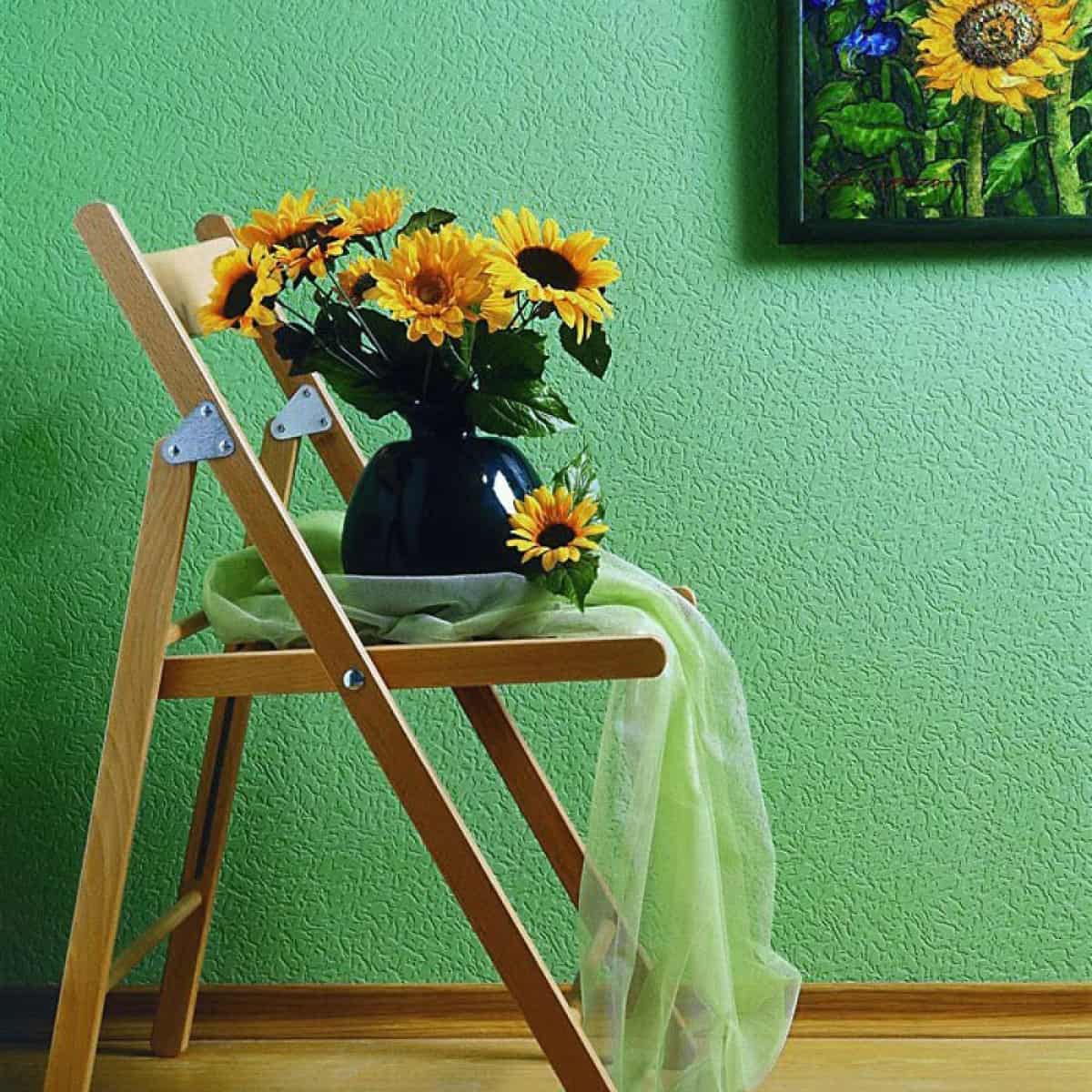 colt de bucatarie cu tapet verde cu scaun maro cu ghiveci cu floarea soarelui si tablou pe perete
