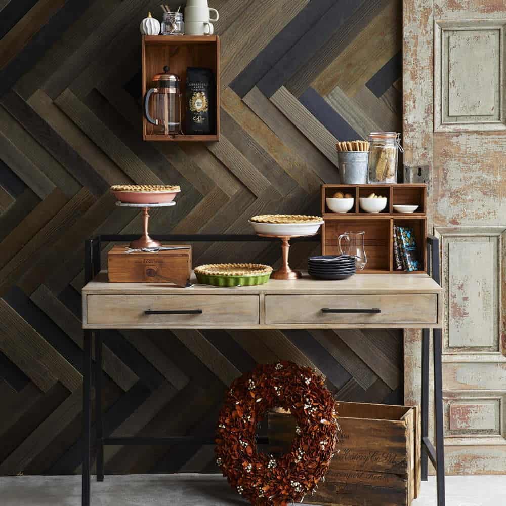 camera decorata cu panbou decorativ rustic de culoare maro si mobilata cu o masuta din lemn pe care sunt asezate farfurii cu placinta