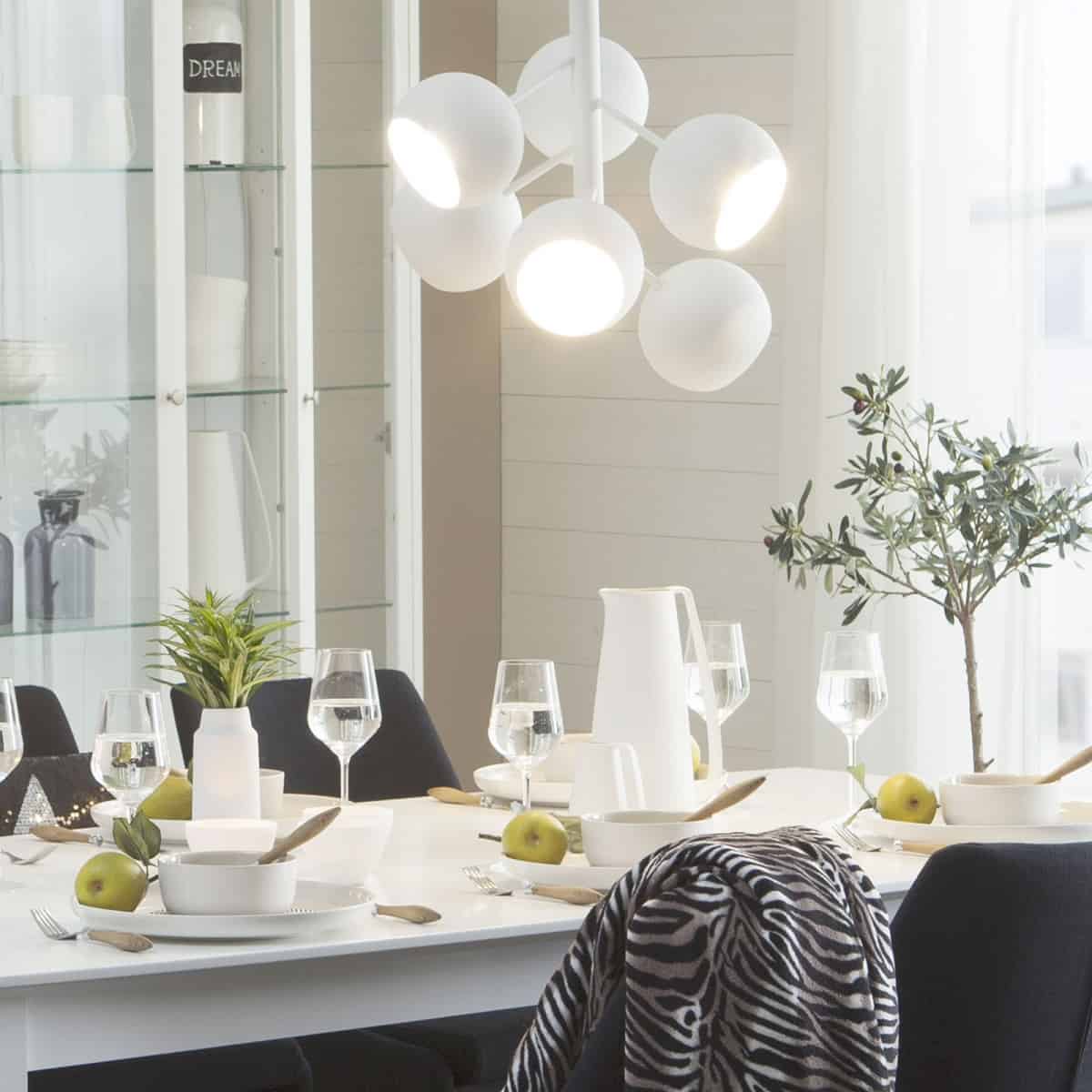 lustra suspendata alba cu sase globuri metalice asezata deasupra unei mese intr-o camera de dining decorata cu alb, crem, negru si verde