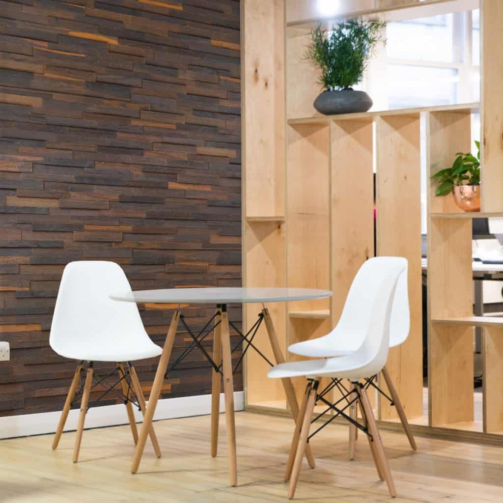 Perete cu panouri decorative din lemn de stejar intr-un living cu masa si scaune si rafturi din lemn cu flori decorative