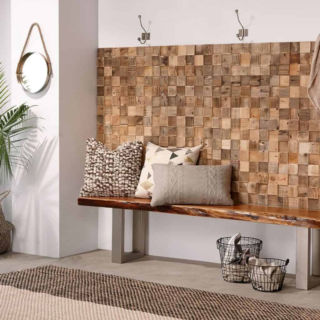 Perete cu panou decorativ din lemn intr-o incapere cu banca si perne decorative si doua cosuri