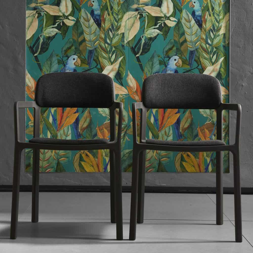 Perete cu faianta pictata cu vegetatie si papagali, in fata caruia se afla doua scaune negre