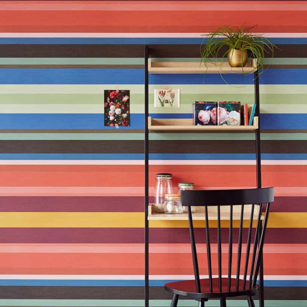 Tapet Masterpiece cu benzi orizontale colorate in camera cu rafturi cu obiecte decorative si scaun