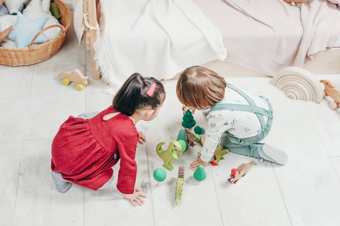 doi copii baiat si fata care se joaca intr-o camera decorata cu mult alb