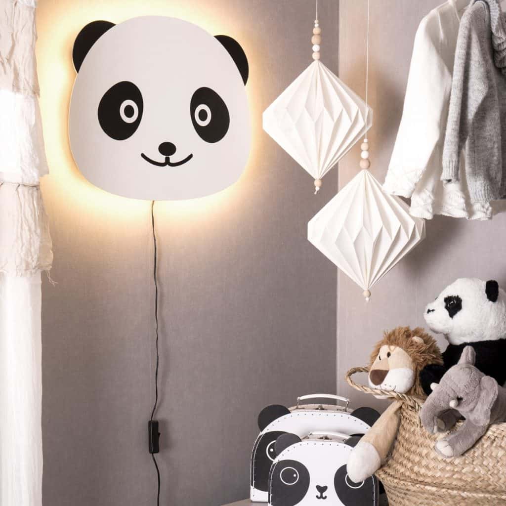 Aplica de perete Panda, intr-o camera cu jucarii, haine pe umerase, obiecte decorative suspendate si doua genti panda