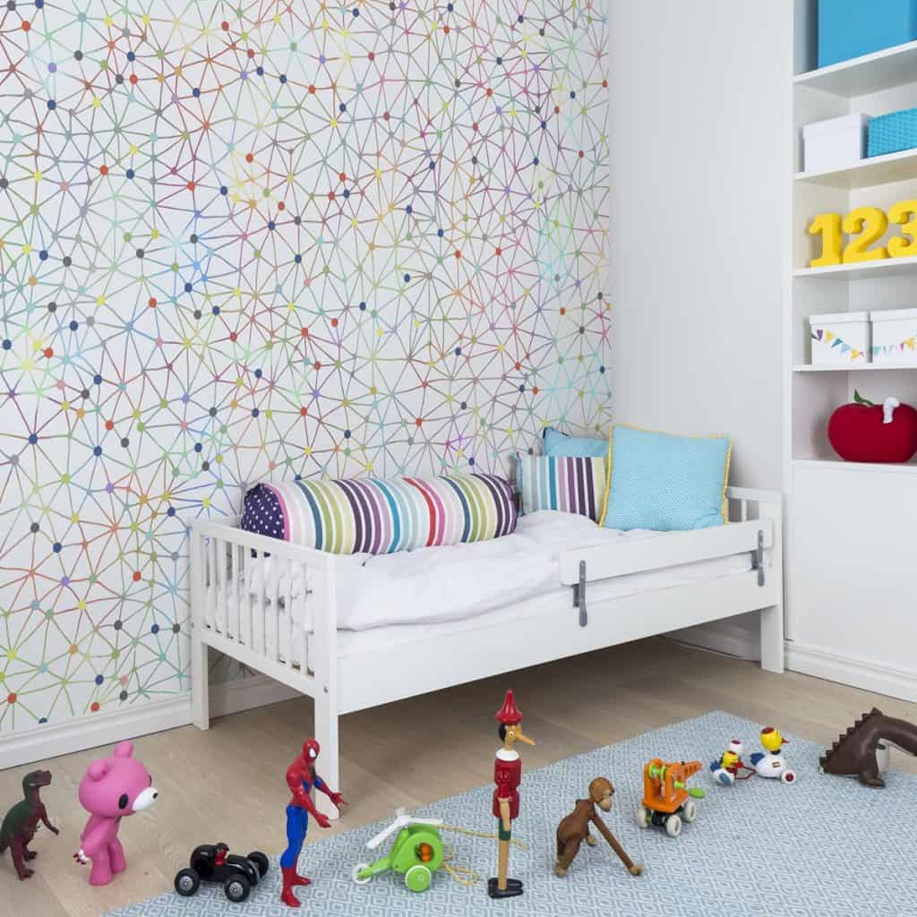 Fototapet Twinkle Twinkle in camera unui copil cu pat si dulap albe, cu accesorii colorate si cu jucarii asezate intr-un sir pe podea si covor