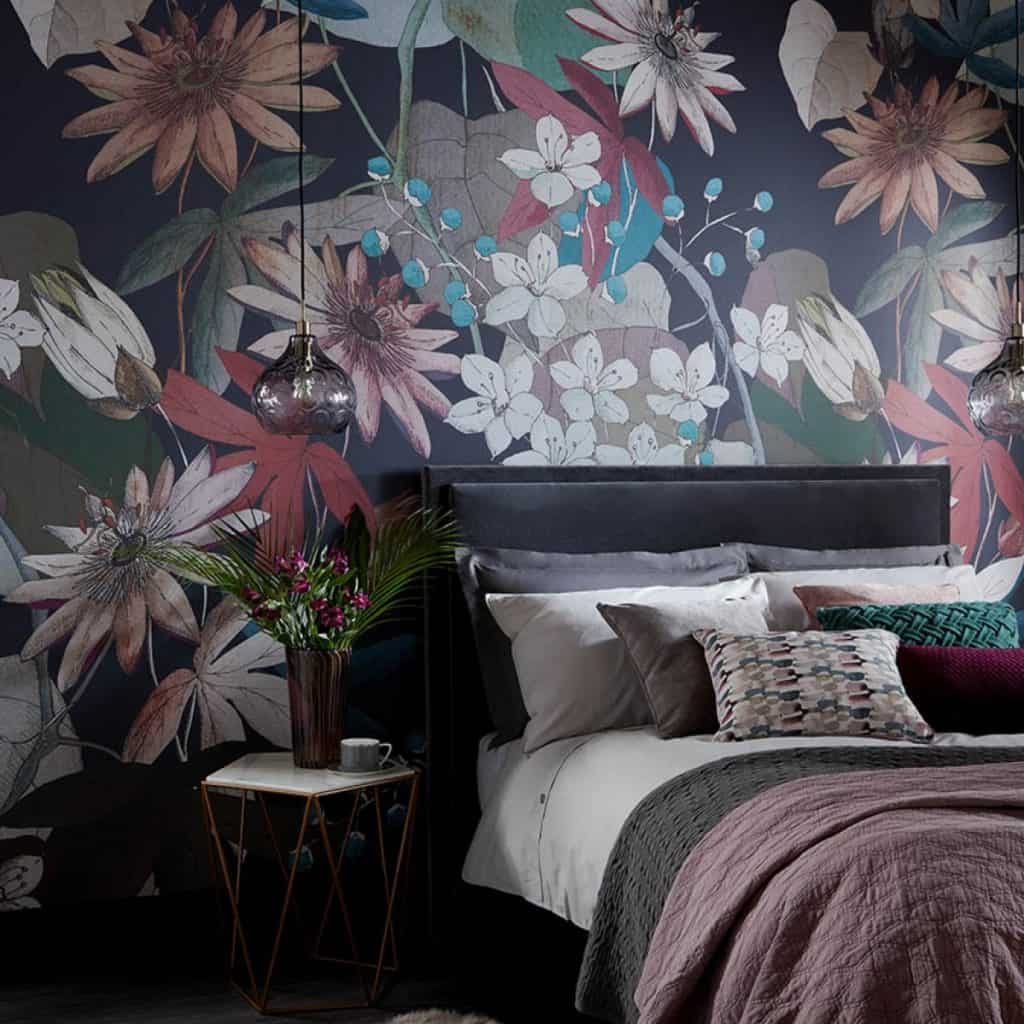 Tapet Clematis intr-un dormitor cu pat cu mai multe perne decorative si noptiera pe care se afla un vas cu flori si o ceasca de cafea