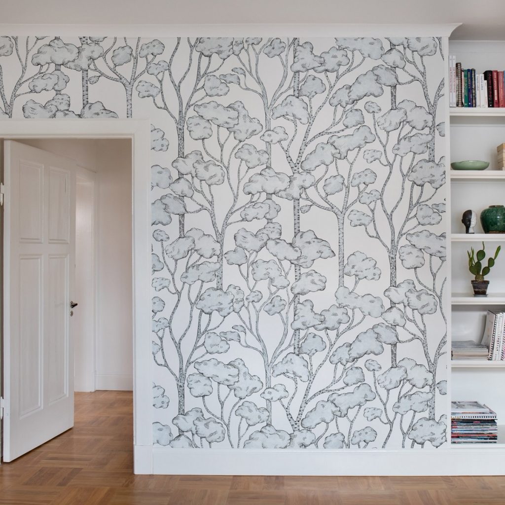 Fototapet Animal Tree, personalizat, Rebel Walls, pe un perete cu usa alba si rafturi cu carti si obiecte decorative