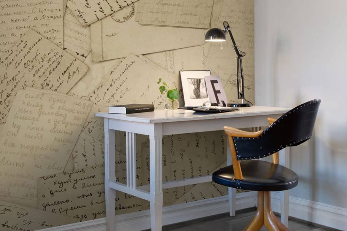 Fototapet 3D Corespondență, Rebel Walls, intr-o incapete cu birou alb pe care se afla o lampa, carte si obiecte decorative și scaun negru