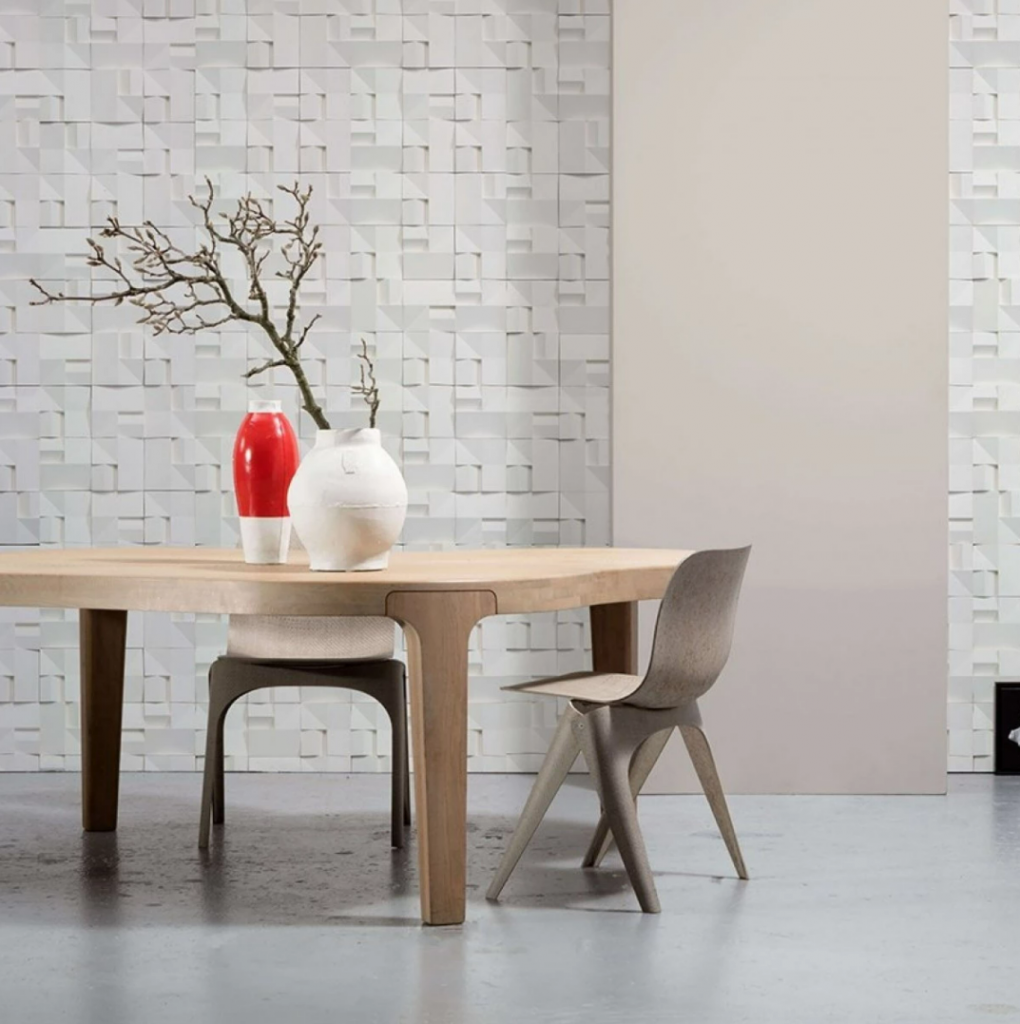 Tapet designer House Ceramics by Studio Roderick Vos, VOS-02, NLXL, intr-o incapere cu masa rotundă din lemn pe care se afla un vas rosu si o vaza cu planta si doua scaune