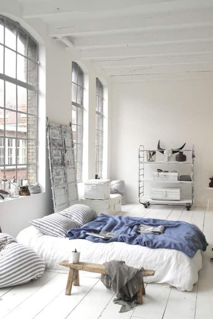 Lemnul este cel mai popular material utilizat în stilul Loft, deoarece este un material versatil, putând fi utilizat în lucrări de proiectare a pardoselii, pereților sau pentru mobilier Dormitor alb cu ferestre inalte si largi cu pardosea de culoare alba si pat jos