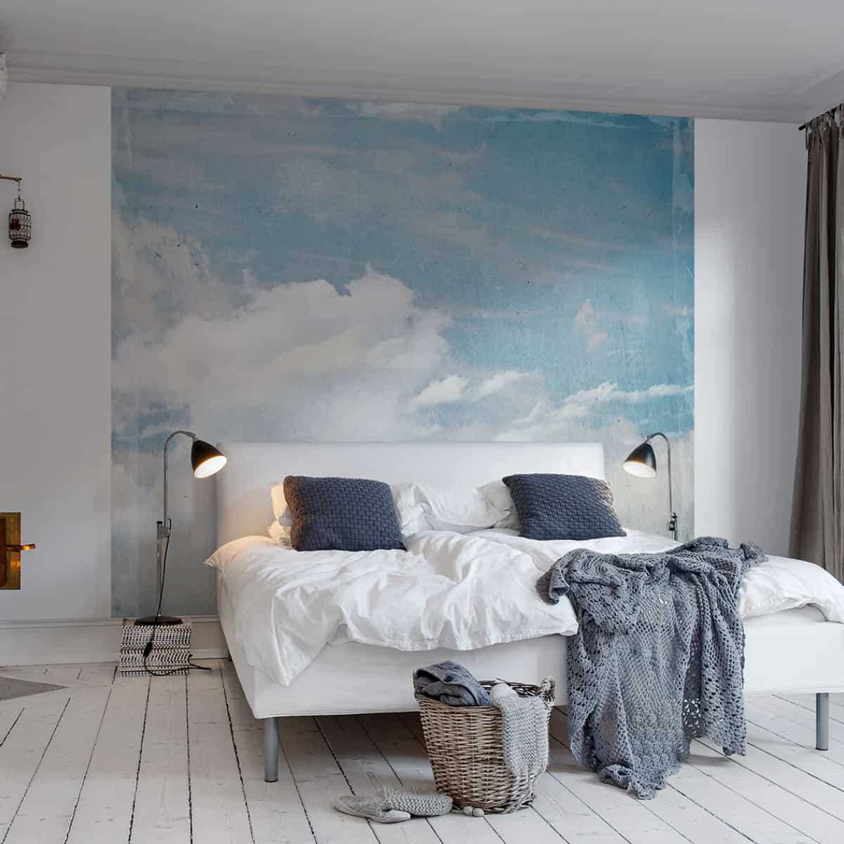 dormitor decorat cu tapet in nuate de bleu si alb, care imita cerul cu nori, cu patdublu cu lenjerie alba si albastra, si podea alba