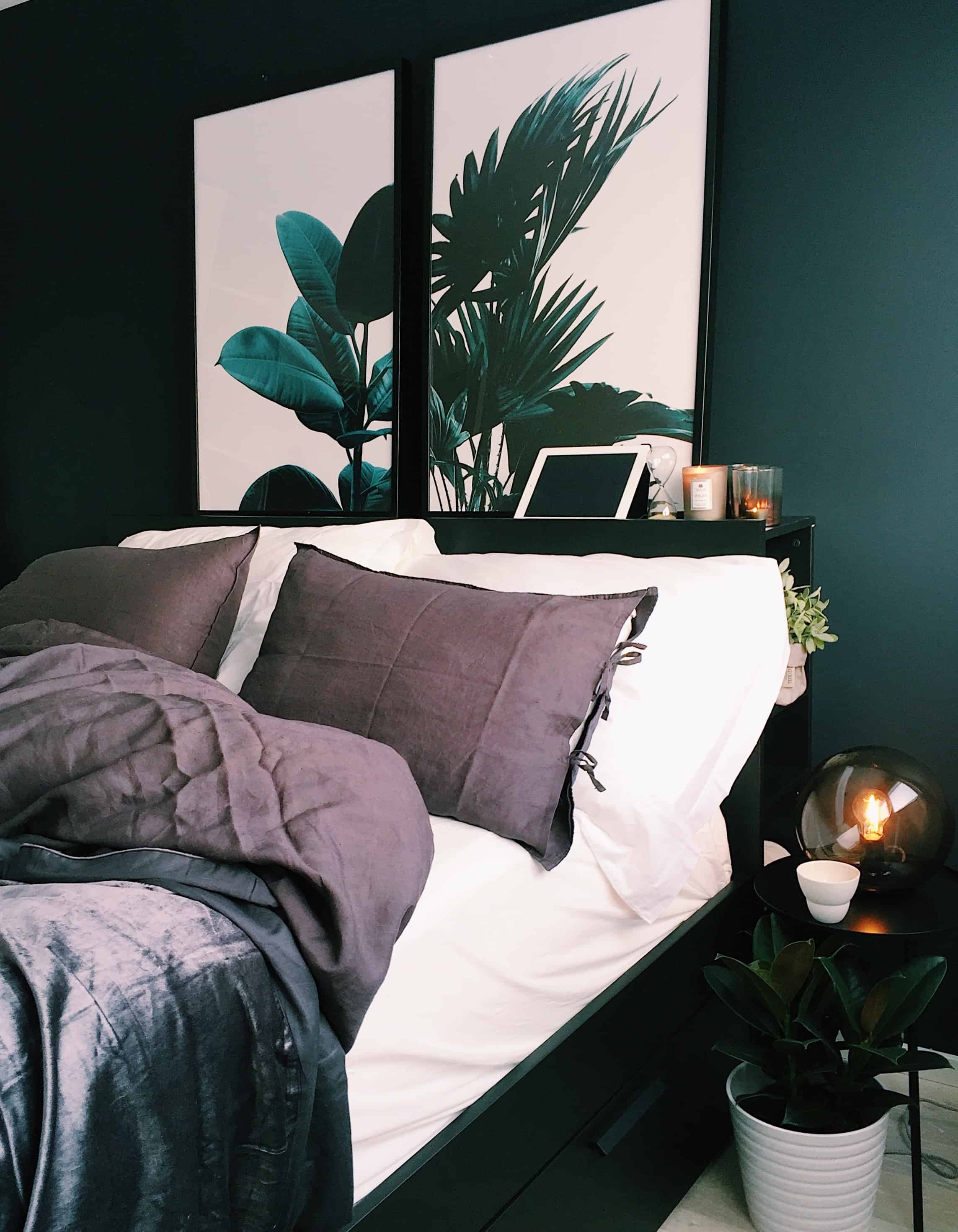dormitor cu pereti de culoare verde intens, cu pat dublu alb cu maro și obiecte de decor negre si albe