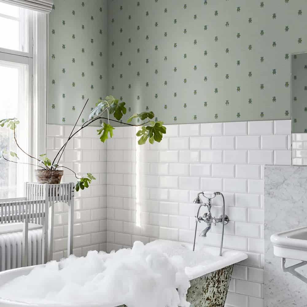 baie decorata cu placi de faianta albe si fototapet verde si mobilat cu o cada plina cu spuma