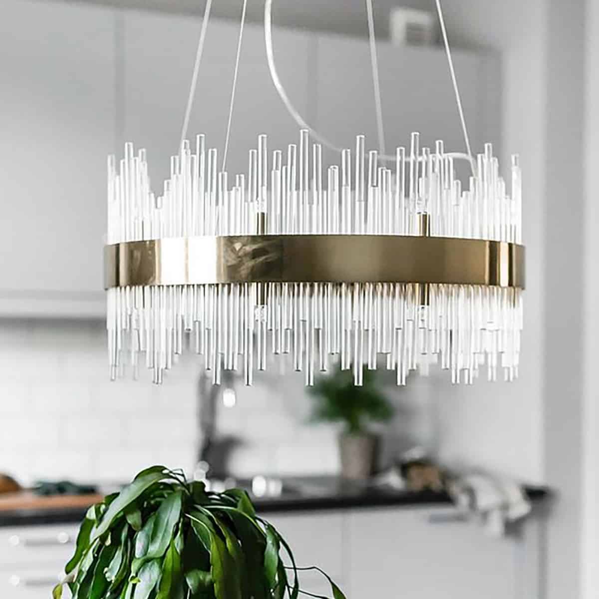lustra suspendata soho lux din metal de culoarea alamei cu tuburi din sticla intr-o bucatarie open space alba cu negru si elemente de decor verzi