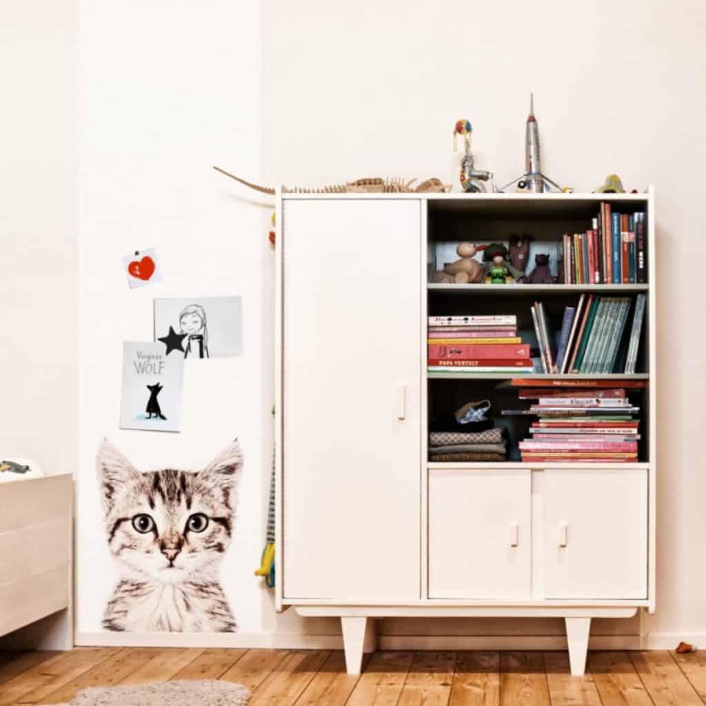 Tapet magnetic cu pisica aplicat pe un perete langa care se afla un dulap cu rafturi pentru carti