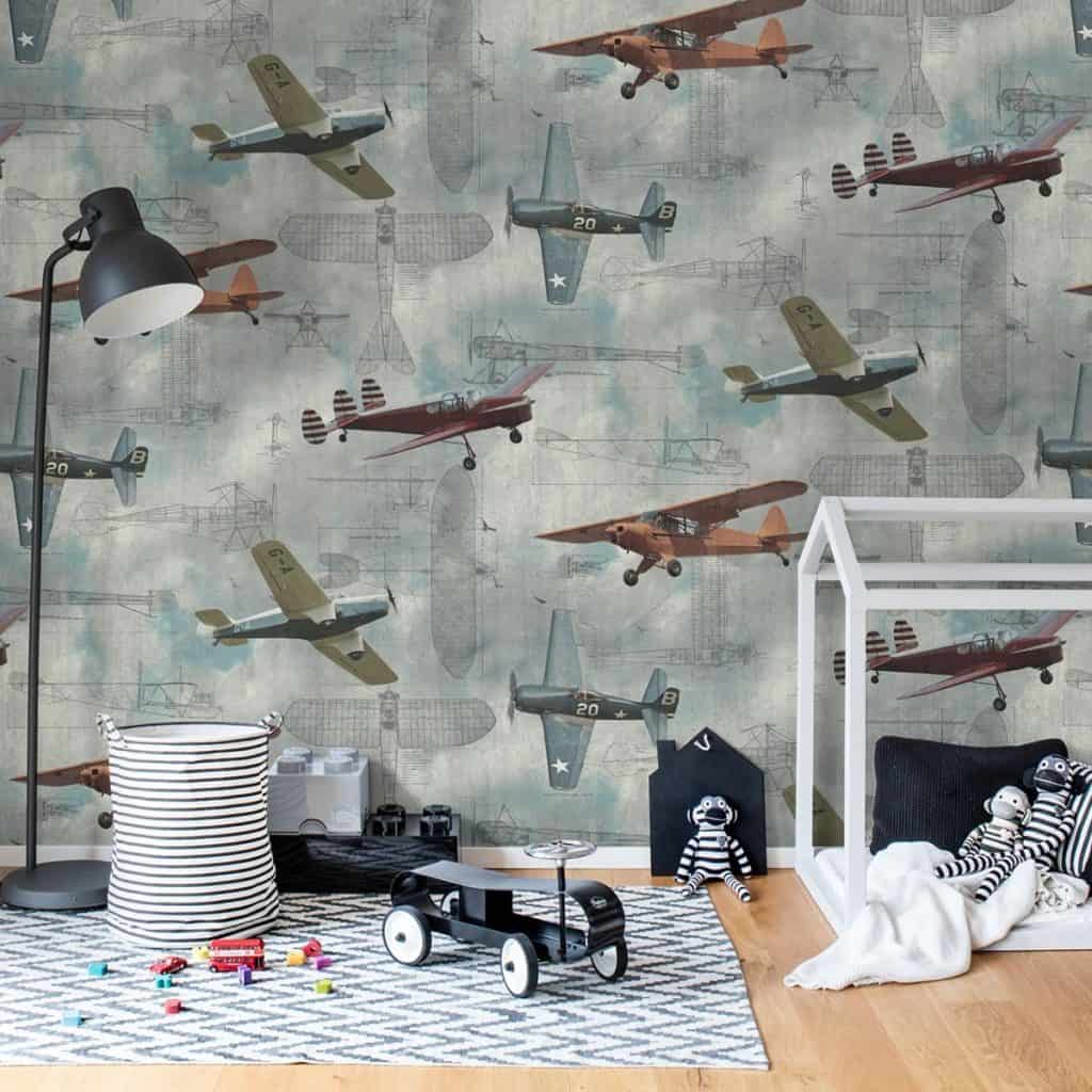 Perete decorat cu fototapet cu avioane intr-o camera cu jucarii si cu covor pe podea