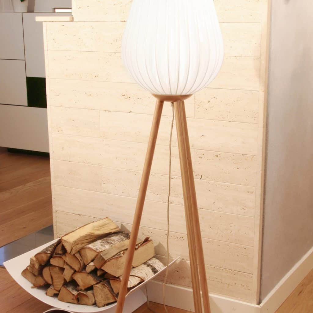 Lampadar cu glob alb in fata unui perete, langa lemne pentru foc