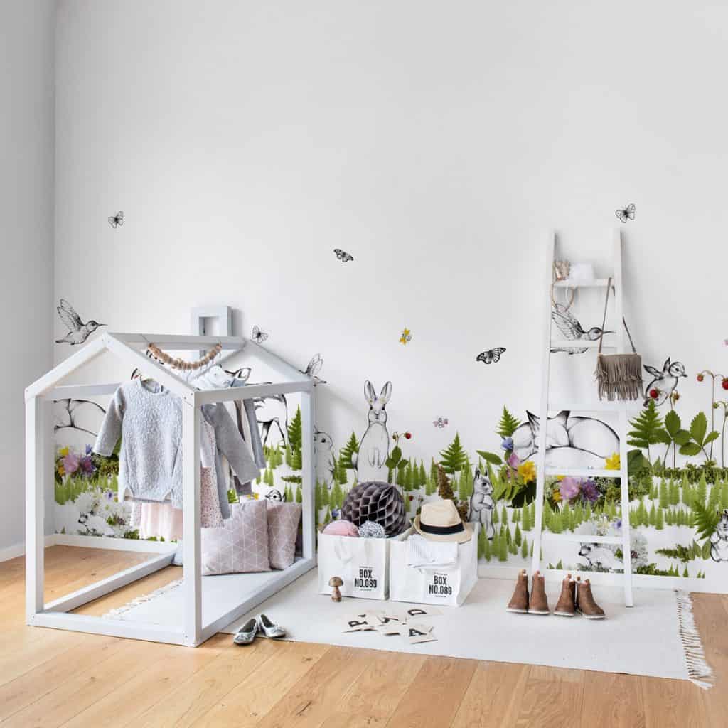 Camera unui copil amenajata cu fototapet cu motive inspirate din natura cu covor alb, elemente de mobilier si incaltaminte