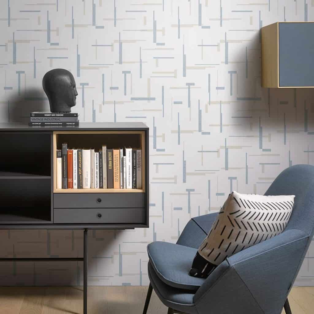 Living cu perete cu imprimeuri geometrice, cu fotoliu, comoda cu carti si elemente de decor