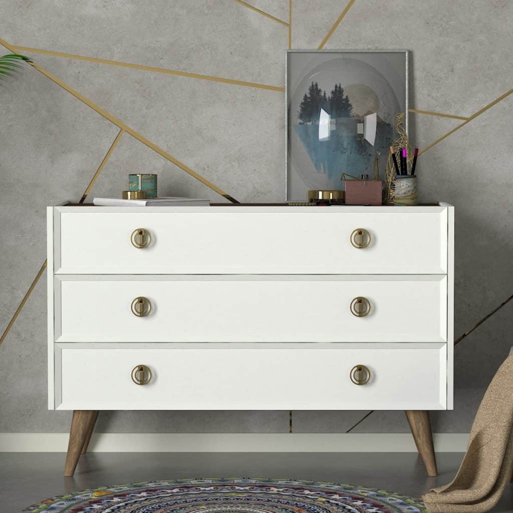 Comoda de culoare alba, cu trei sertare, pe care se află obiecte decorative