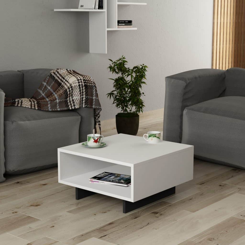 Masuta de cafea alba, cu doua cesti de cafea si o revista pe raftul inferior, intr-un living cu doua fotolii si planta decorativa