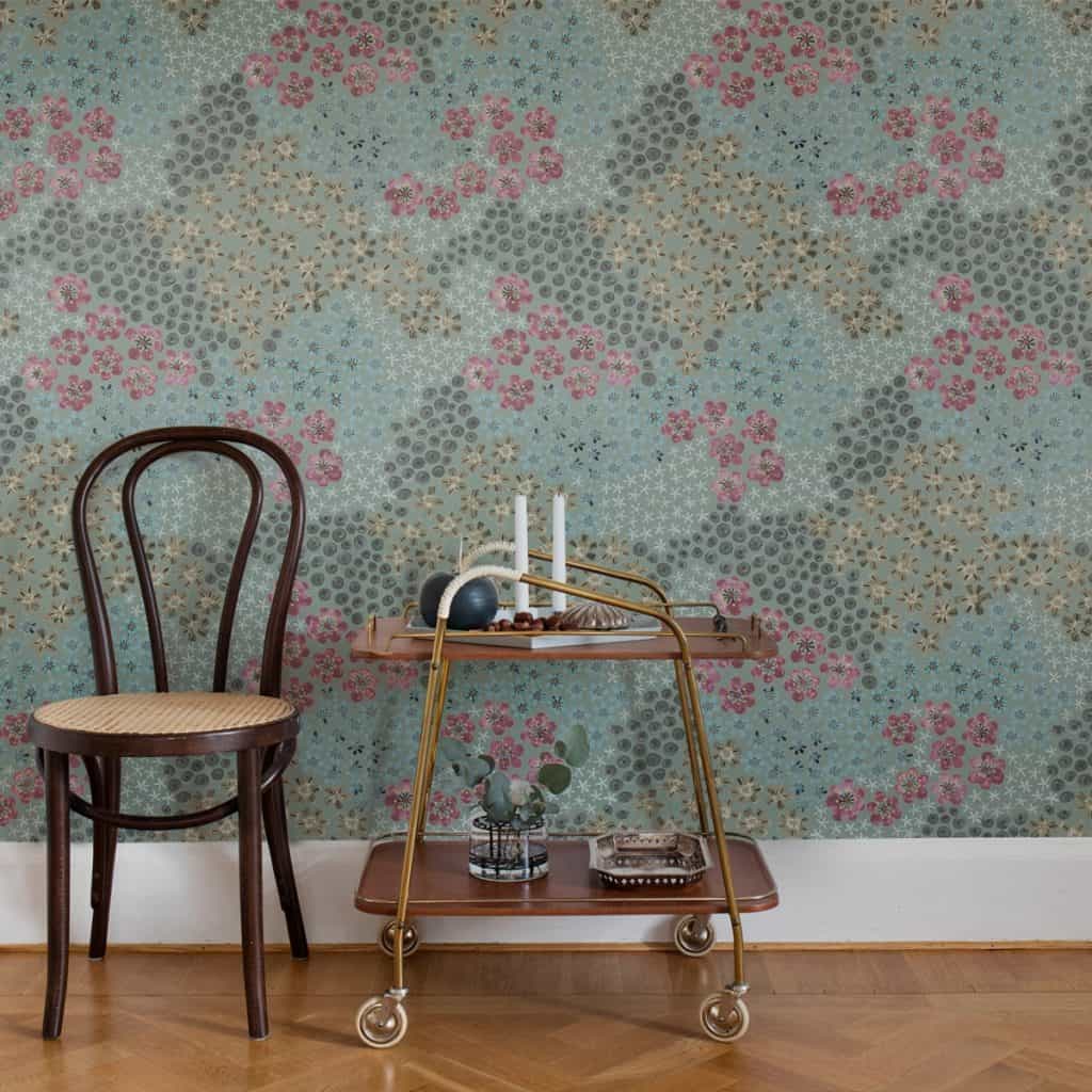 Perete cu fototapet cu flori colorate, in fata caruia se afla un scaun si o masa cu obiecte decorative