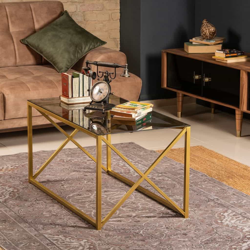 Masa de cafea pe care se afla carti si un obiect decorativ, intr-un living cu canapea si comoda