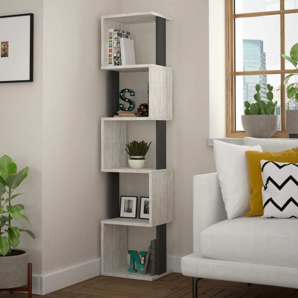 Bibliotecă deschisa la culoare in coltul unui living cu fereastra cu planta decorativa, canapea alba pe care se afla trei perne