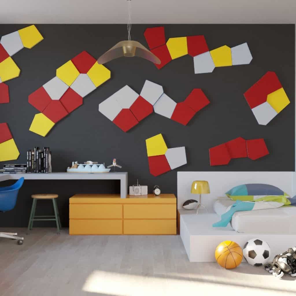 Dormitor cu perete accent cu panouri decorative gri, roșu, galben și alb, cu pat, birou si doua mingi