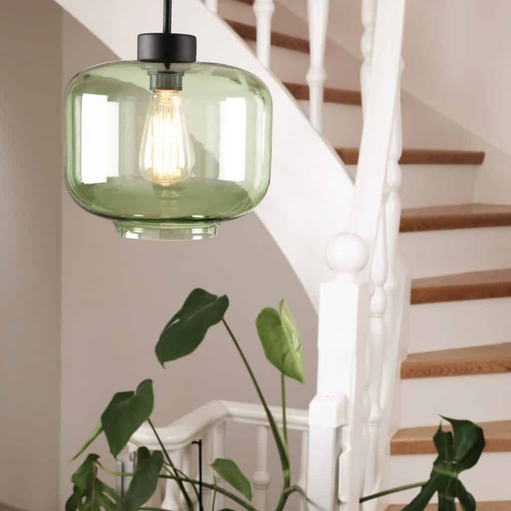 Lampa suspendata Ritz din sticla de culoare verde intr-o incapere cu scara interioară si planta decorativă