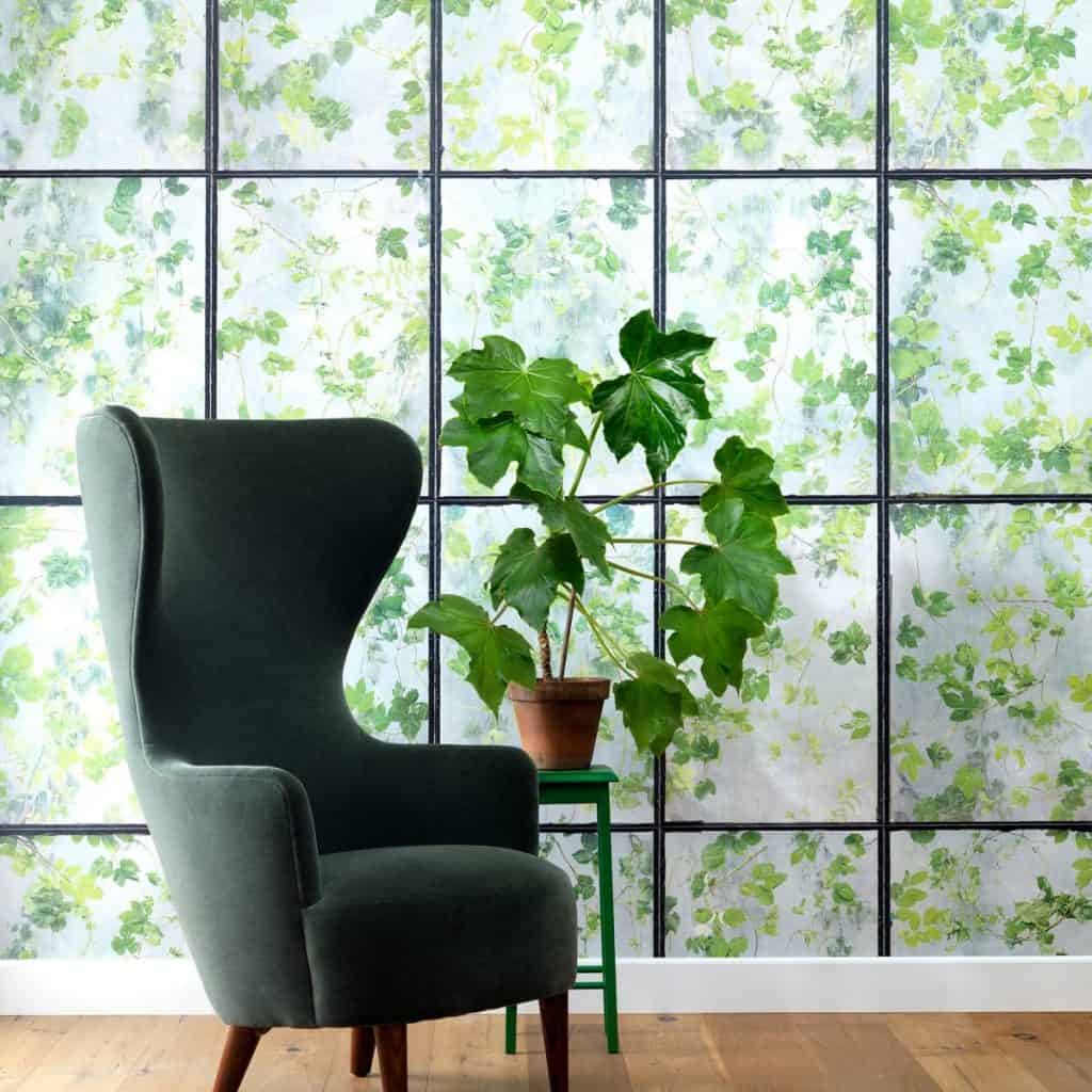 Perete cu tapet greenhouse intr-o incapere cu planta decorativa si fotoliu gri inchis