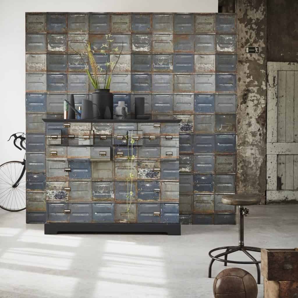 Perete cu tapet Container Dark si comoda reconditionata cu acelasi tapet, pe care se afla mai multe vase decorative si o planta, intr-o incapere cu scaun si minge, decorata in stil industrial