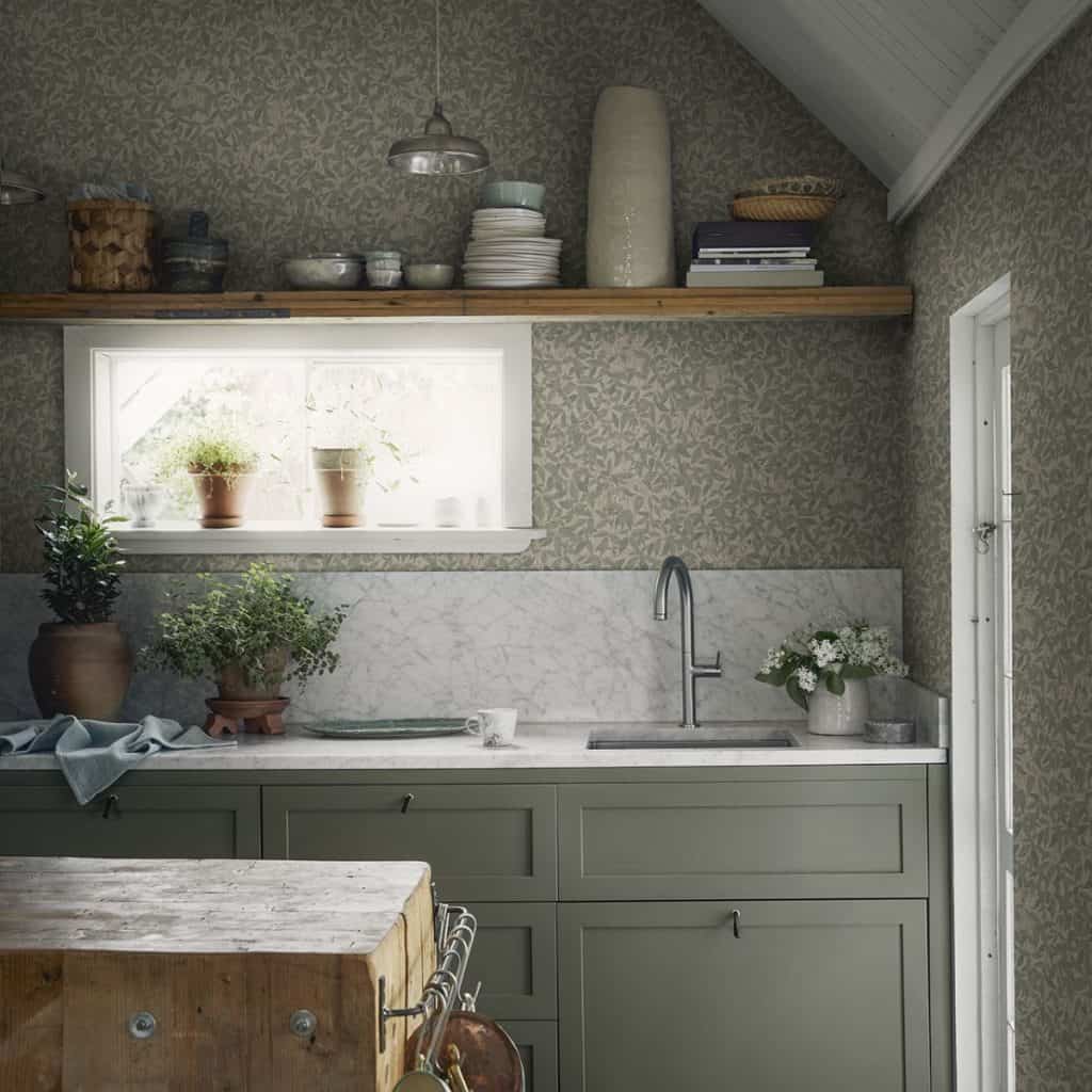 Tapet Linnea Garden Green intr-o bucatarie cu mobila alb cu gri, polita cu vase, plante decorative si o insula din lemn