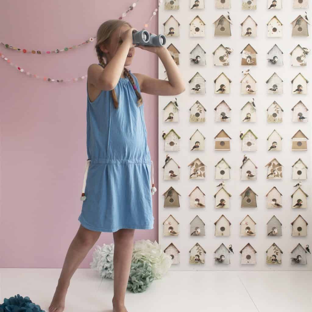 Tapet Birdhouses in fata caruia se afla o fata cu rochie albastra care se uita prin binoclu