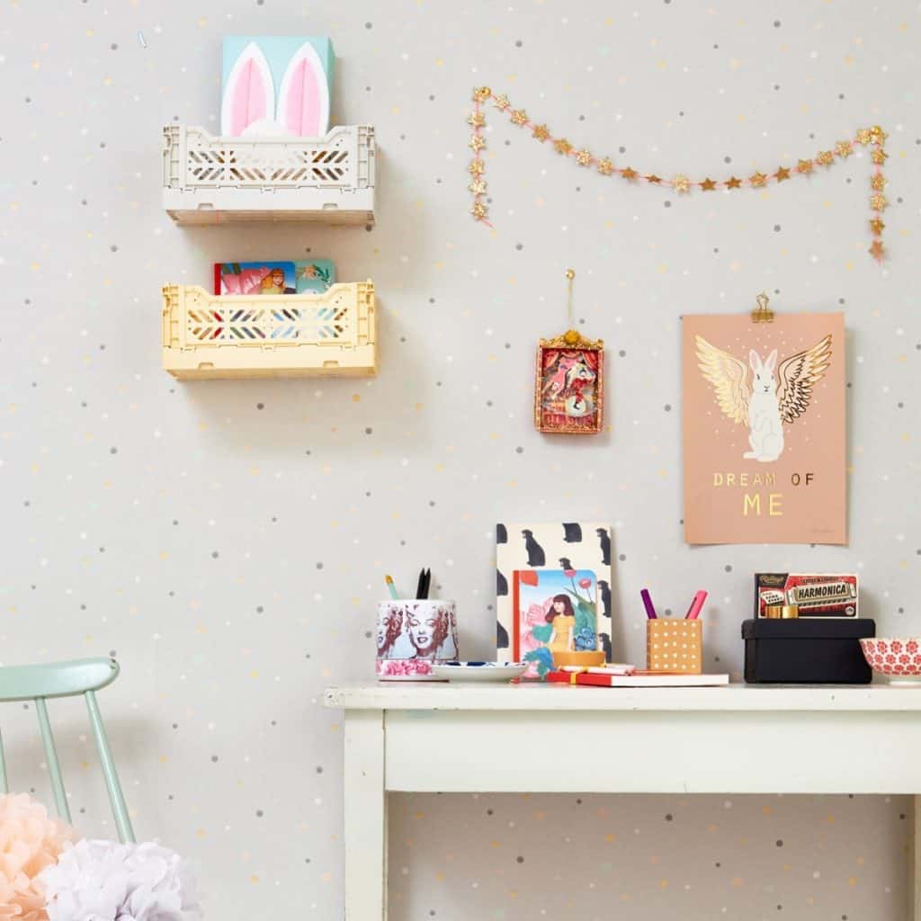 Tapet Stardust intr-o camera cu masa alba pe care se afla rechizite si obiecte decorative, cu doua tablouri, doua polite cu jucarii si o ghirlanda