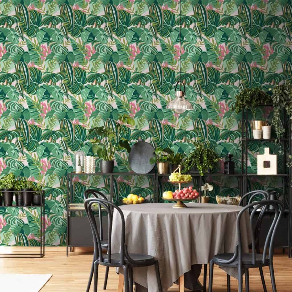 Tapet Tropical Foliage intr-o incapere cu un suport metalic pe care se afla plante si obiecte decorative, masa pe care se afla un cos cu fructe si patru scaune negre