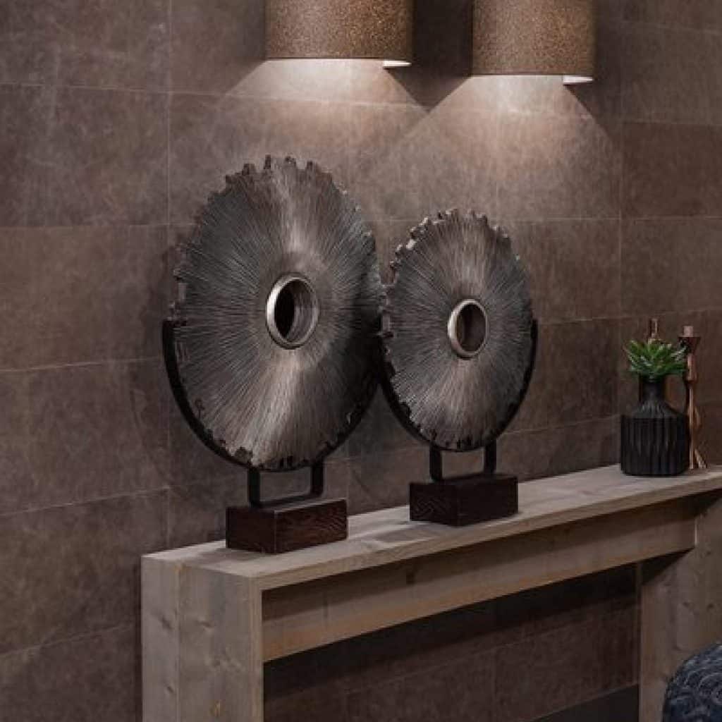 Tapet din piele Enzo Pellini Taupe pe un perete pe care se afla doua aplice, in fata caruia se afla un suport cu doua obiecte decorative circulare si un vas cu floare