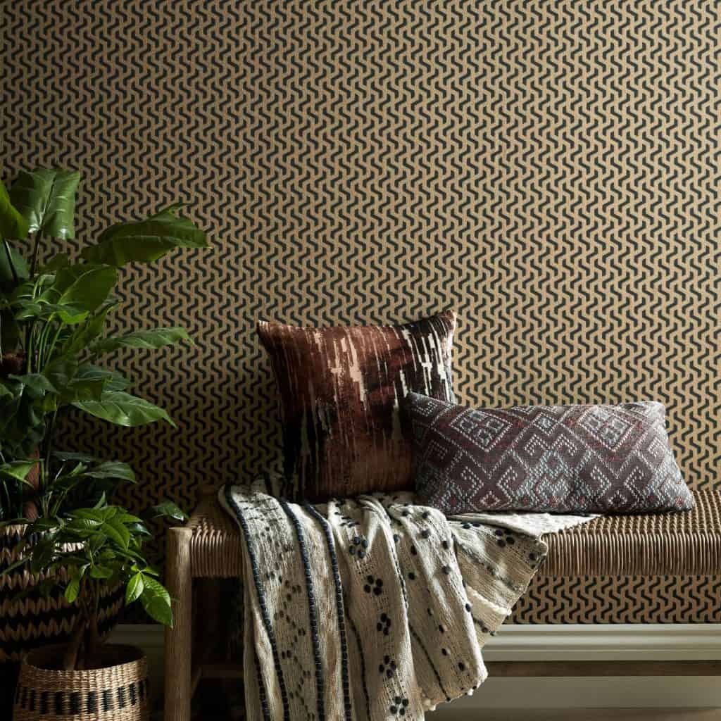 Tapet Rattan pe un perete in fata caruia se afla o banca pe care se afla doua perne decorative si un pled, langa care se afla un vas cu planta decorativa