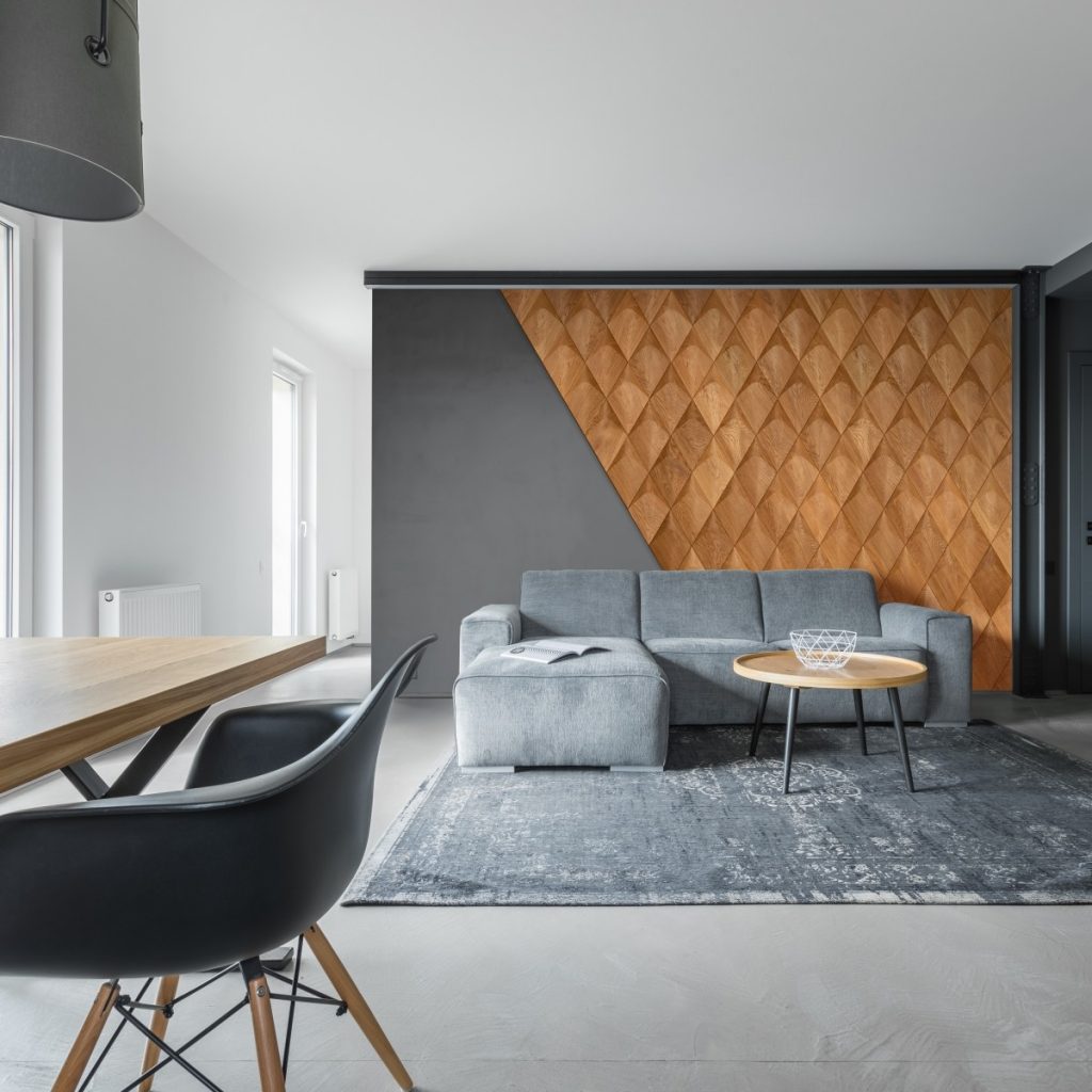 Panouri decorative 3D din lemn de stejar Caro Plus intr-un living cu canapea si covor gri si masa cu scaun