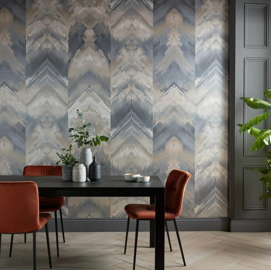 Tapet Reflections, 1838 Wallcoverings, intr-un living cu masa neagra pe care se afla vase decorative si plante si trei scaune maro