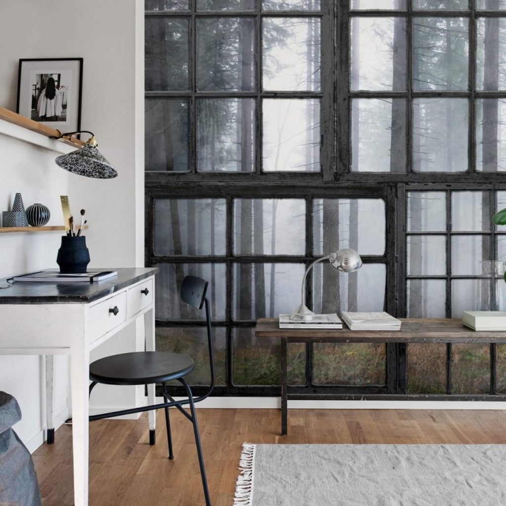 Fototapet 3D Cabana, personalizat, Rebel Walls, intr-o incapere cu birou alb cu un vas cu obiecte de scris, polite cu obiecte decorative, scaun negru, covor gri si o banca din lemn pe care se afla o lampa si reviste
