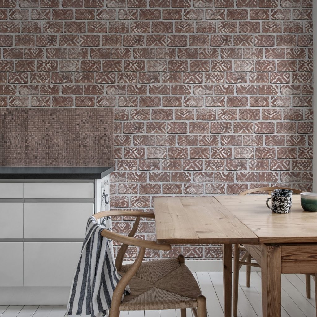 Fototapet Caramizi decorate, rosu, personalizat, Rebel Walls, intr-o incapere cu bufet alb cu blat negru si masa din lemn pe care se afla doua cani alb cu negru si un bol, si un scaun