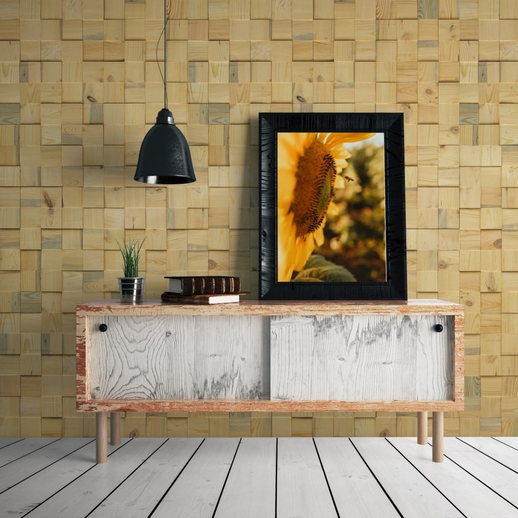 Panouri decorative din lemn de pin, Solid Mystic, Cubetti, intr-o incapere cu comoda din lemn pe care se afla un vas cu planta decorativa, doua carti si un tablou cu o floarea-soarelui, si un corp suspendat de iluminat de culoare neagra