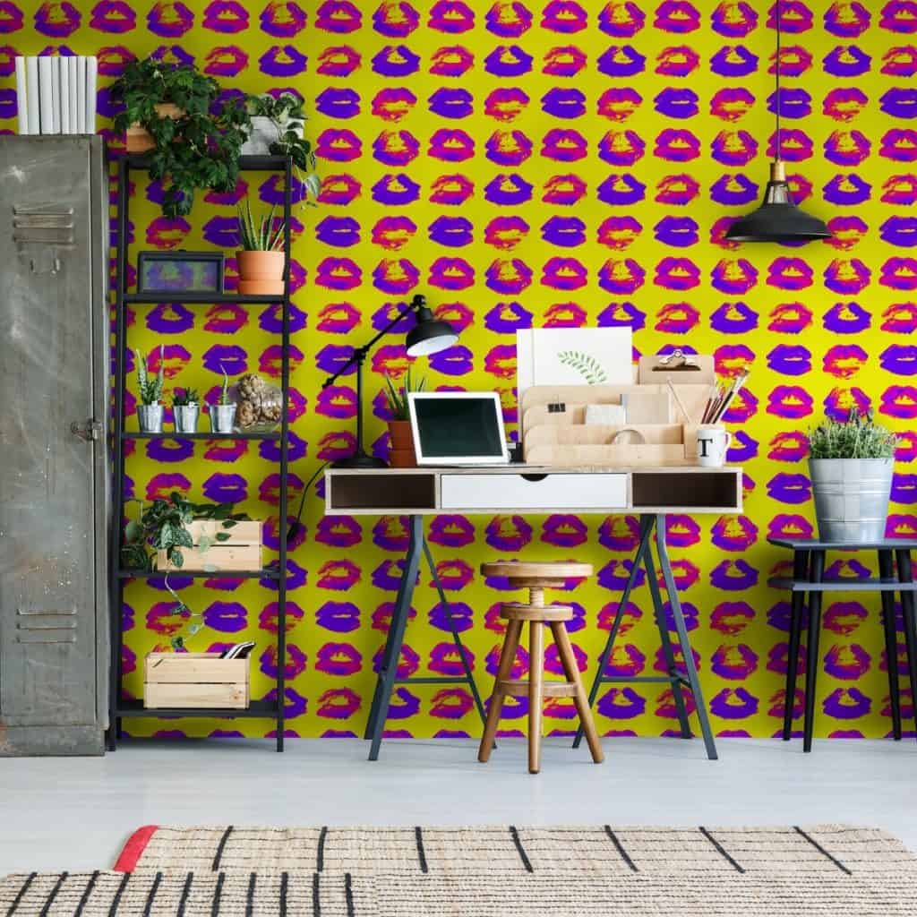 Tapet designer Neon Kiss, Mindthegap, intr-o incapere cu birou pe care se afla un laptop, un suport din lemn si instrumente pentru pictura, scaun din lemn, masuta cu vas cu planta decorativa in dreapta si in stanga cu rafturi cu obiecte decorative si dulap metalic