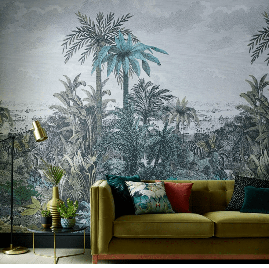 Tapet Paradise Found, 1838 Wallcoverings, intr-o incapere cu canapea verde si perne decorative, masuta de cafea pe care se afla vase cu plante decorative si lampa de podea aurie